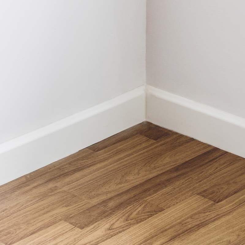 Laminated wood floor with white wall, room corner